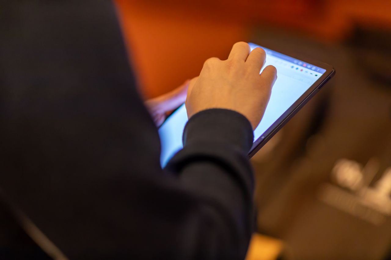 heros-img Close-up of a person using a tablet, showcasing technology and modern lifestyle.