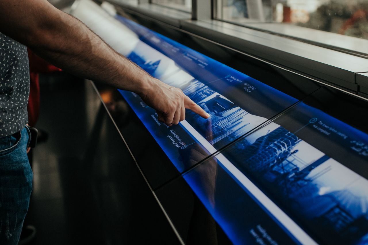 about-us Close-up of a person interacting with a touchscreen display in a modern environment.